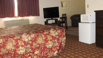 Una habitación de hotel con cama, televisor, microondas y refrigerador.