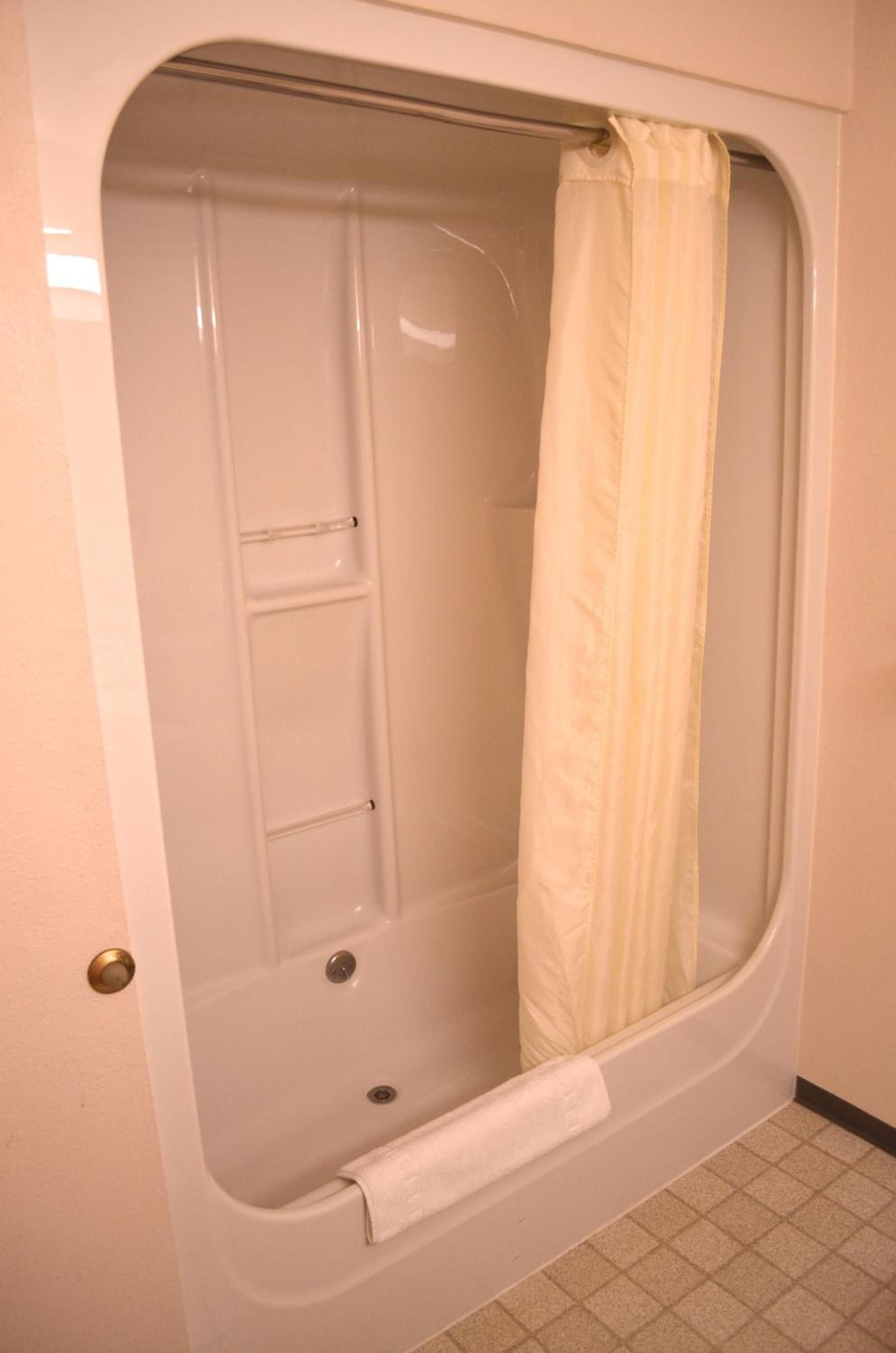 A bathtub with a shower curtain, a towel, and a drain.