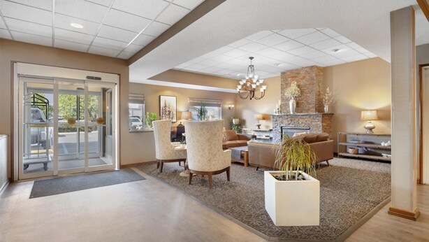 A spacious lobby with a modern design, featuring a seating area with armchairs and a coffee table, a fireplace, and a chandelier. - Best Western Plus City Center (Spokane)