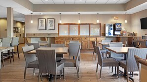 A restaurant with a long counter, wicker chairs, and a television screen. - Best Western Plus City Center (Spokane)