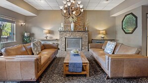 A living room with leather sofas, a wooden coffee table, a stone fireplace, and a chandelier. - Best Western Plus City Center (Spokane)