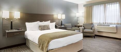 A hotel room with a large bed, two bedside tables with lamps, a chair, and a window with curtains.