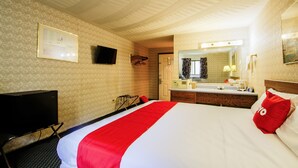 A hotel room with a bed, a TV, a desk, and a bathroom.