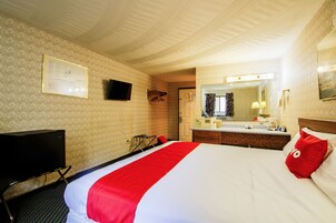 Habitación de hotel con cama, televisión, escritorio y baño.