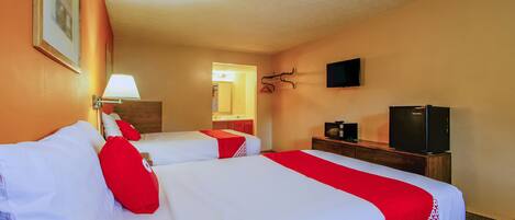 Een hotelkamer met twee bedden, een televisie, een lamp en een spiegel.