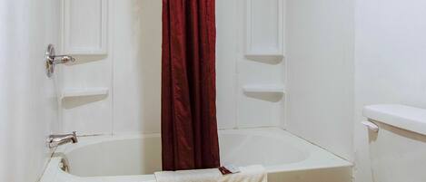 Un baño con bañera, inodoro y cortina de ducha.