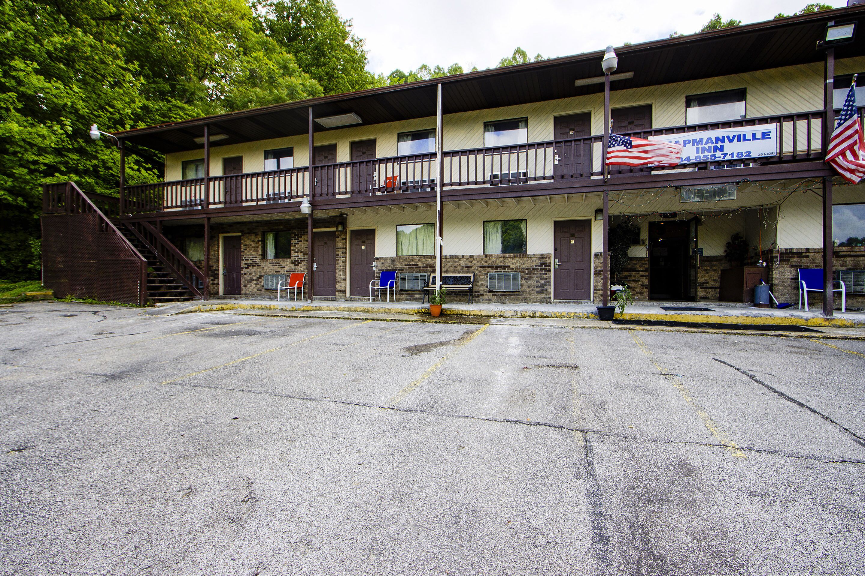 A motel with a two-story structure, a covered front porch, and a parking lot.