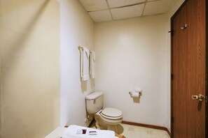 A small, clean bathroom with a toilet, a sink, and a wooden door.