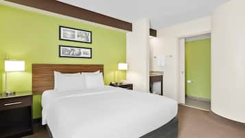 Habitación de hotel con una cama grande, dos lámparas de noche, un cabecero de madera y dos cuadros en la pared.