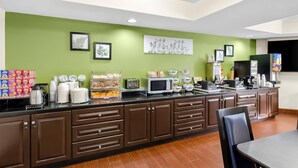 A modern kitchen with brown cabinets, a black countertop, and various appliances. - Sleep Inn & Suites Princeton I-77 (Princeton)