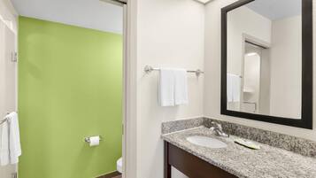A bathroom with a green wall, a white sink, and a large mirror.