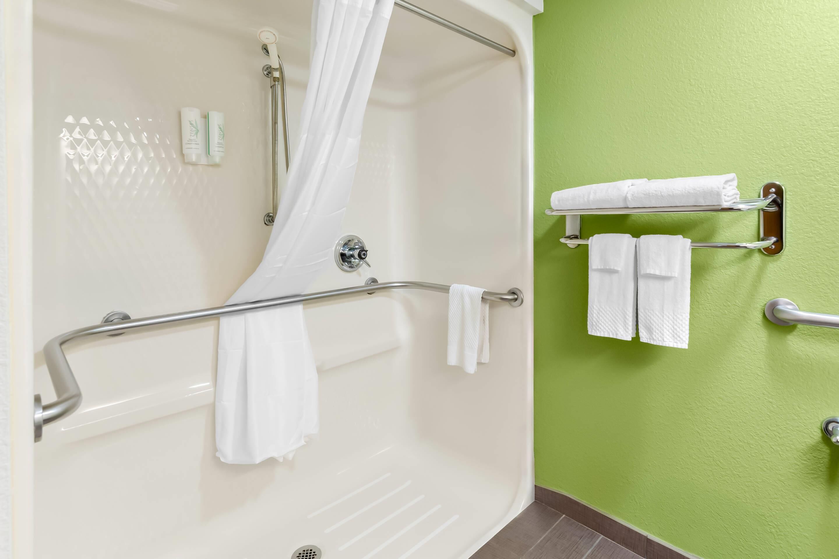 A bathroom with a bathtub, a shower curtain, a towel rack, and a green wall.