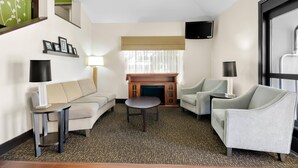 A modern living room with a sofa, two armchairs, a coffee table, a fireplace, and a television mounted on the wall. - Sleep Inn & Suites Princeton I-77 (Princeton)