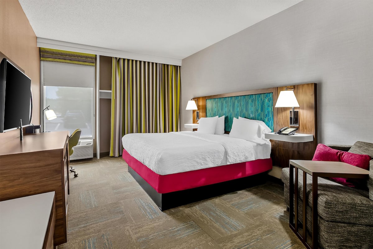 Ein Hotelzimmer mit Bett, Schreibtisch, Stuhl und Fernseher.