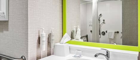 Un baño moderno con un lavamanos blanco, un espejo grande y una ducha.