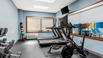 A gym with treadmills, an exercise bike, and dumbbells.