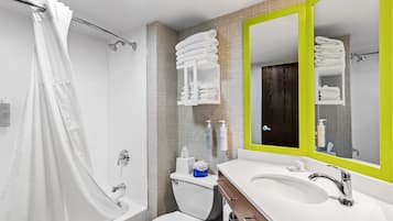 A modern bathroom with a shower, toilet, sink, and a mirror with a green frame.