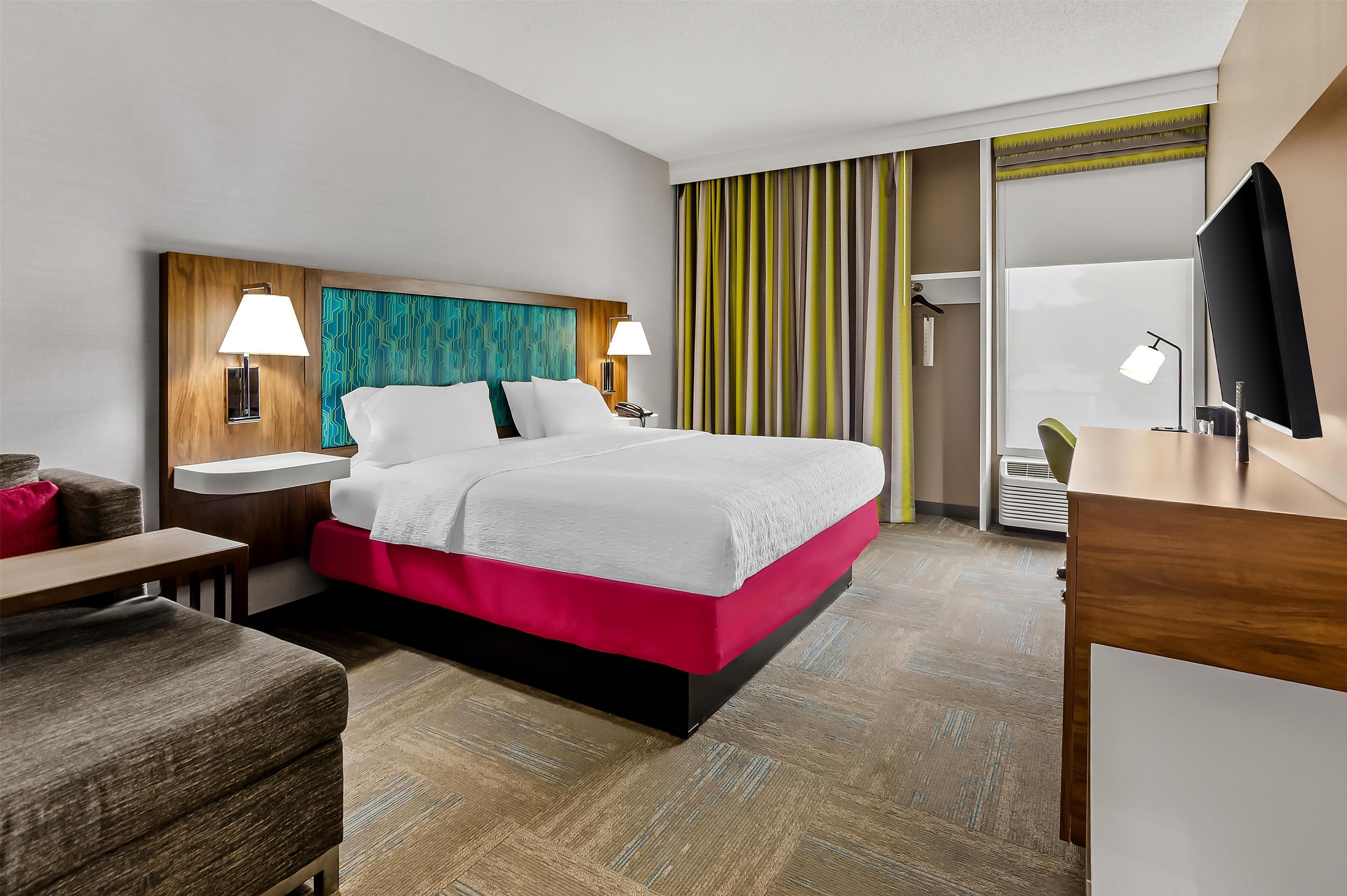 A hotel room with a bed, bedside tables, a desk, and a chair.