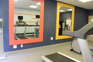 A gym with exercise equipment, including treadmills and a stationary bike, and mirrors on the walls.
