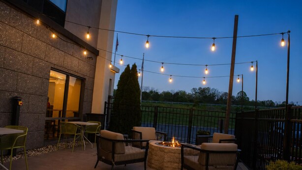 An outdoor patio with chairs, a fire pit, string lights, and a view of the sky. - Hampton Inn Summersville (Summersville)