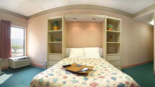 A hotel room with a bed, built-in shelving, a window, and a radiator.