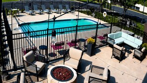 A swimming pool surrounded by a fence, outdoor seating, and a fire pit. - Hampton Inn Summersville (Summersville)