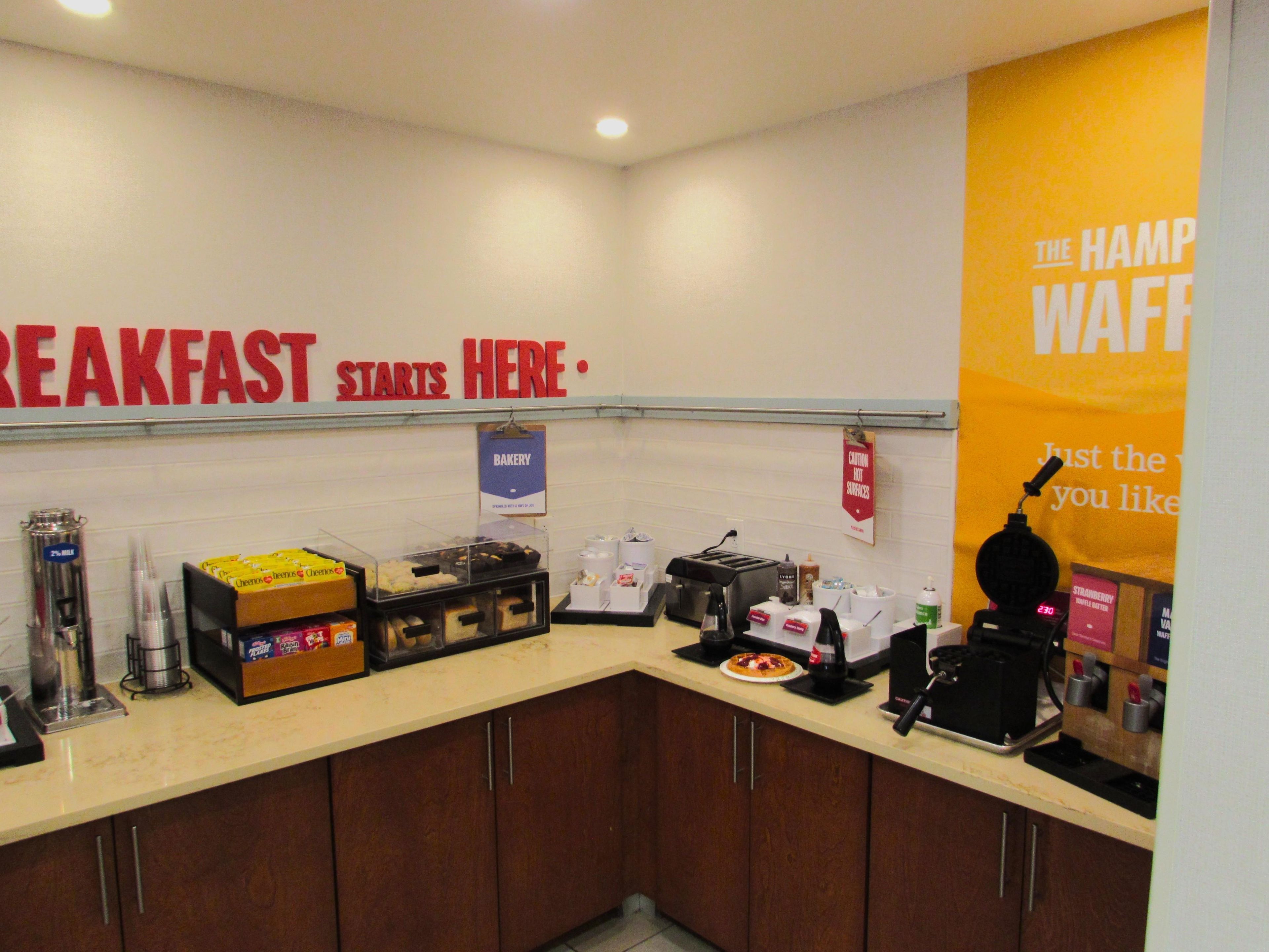 A breakfast area with a sign indicating 'BREAKFAST STARTS HERE.'