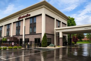 A Hampton Inn with a clear entrance, a parking lot, and a 'welcome' sign.