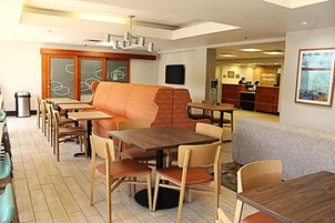 A restaurant with wooden tables and chairs, a cushioned seating area, and a reception desk.