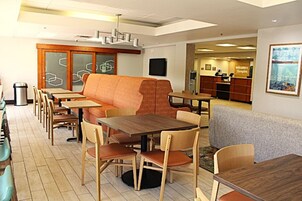 A restaurant with wooden tables and chairs, a cushioned seating area, and a reception desk.