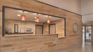 A reception area with a wooden reception desk, framed artwork, and a clock on the wall. - Country Inn & Suites by Radisson, Germantown, WI (Village of Germantown)