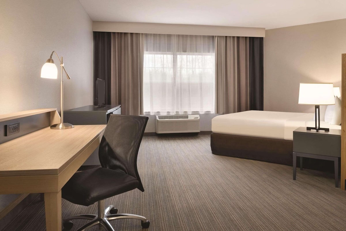 Habitación de hotel con escritorio, silla, cama y mesita de noche.