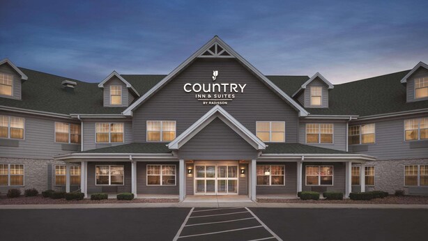 A Country Inn & Suites building with a symmetrical facade, multiple windows, and a parking lot in front. - Country Inn & Suites by Radisson, Germantown, WI (Village of Germantown)