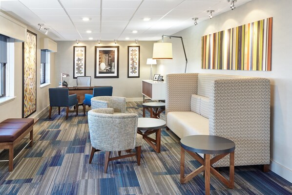 A hotel lobby with a seating area, a reception desk, and framed artwork on the walls.