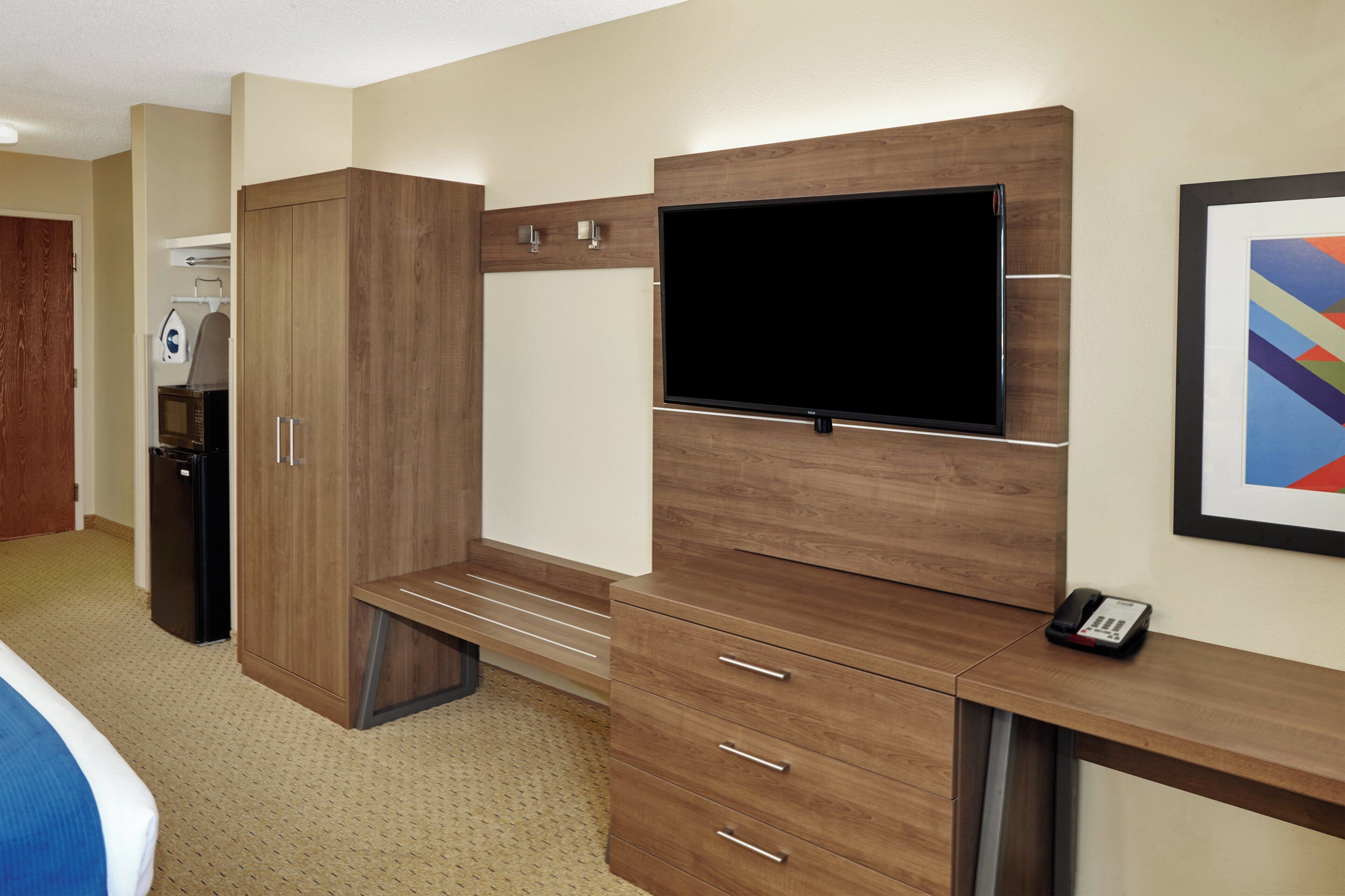 Habitación de hotel con escritorio de madera, televisor de pantalla plana, minibar y microondas.