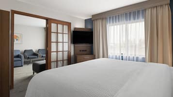 Habitación de hotel con una cama grande, televisión, escritorio y zona de estar con sillas.