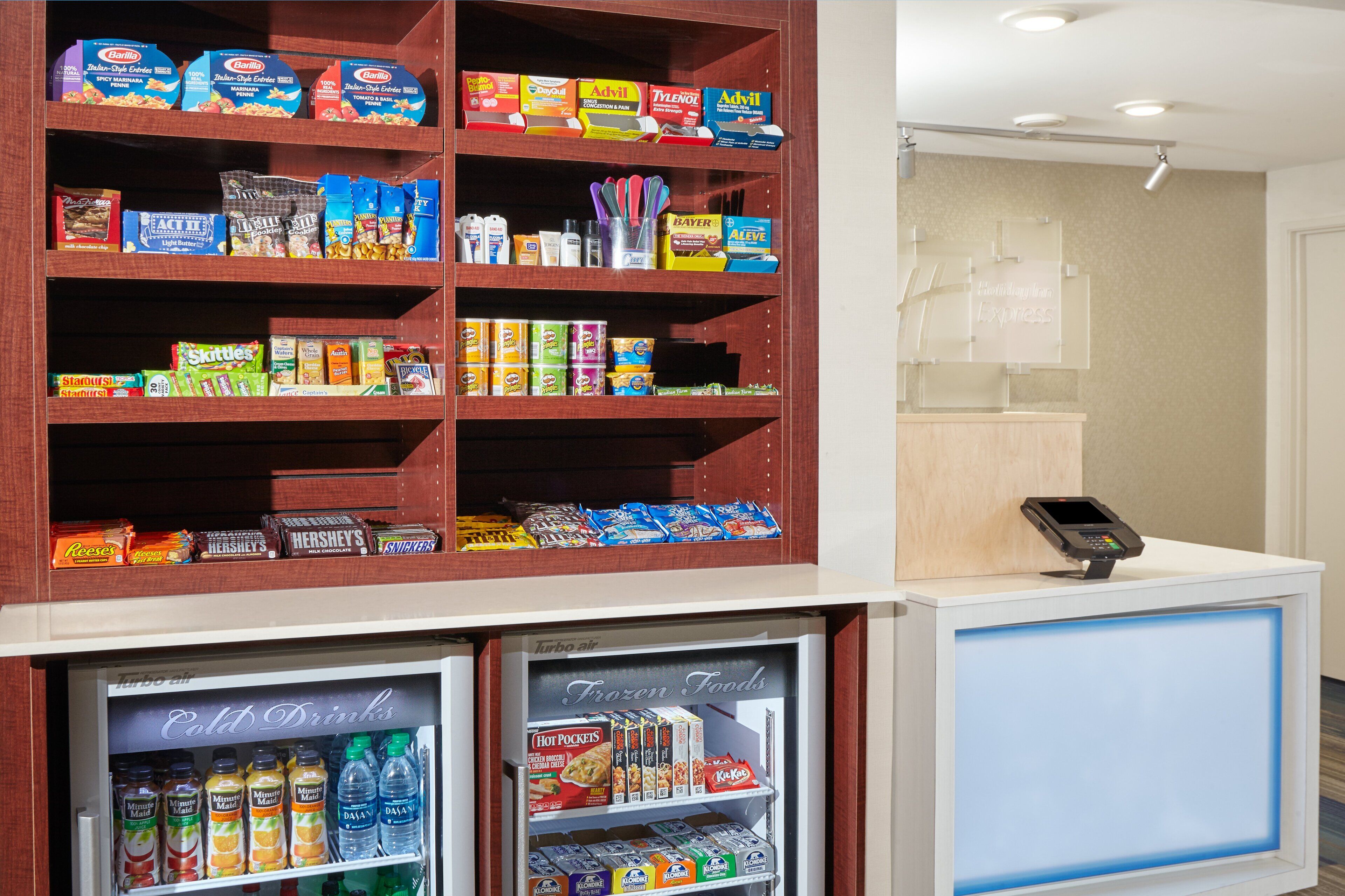 A self-service kiosk with a variety of snacks, including chips and cookies, and a refrigerated section with beverages.