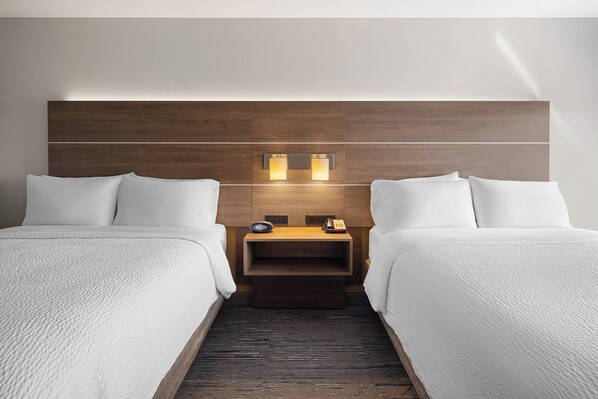 A hotel room with two beds, a wooden headboard, bedside tables with lamps, and a small shelf. - Holiday Inn Express Sheboygan-Kohler by IHG (Sheboygan)
