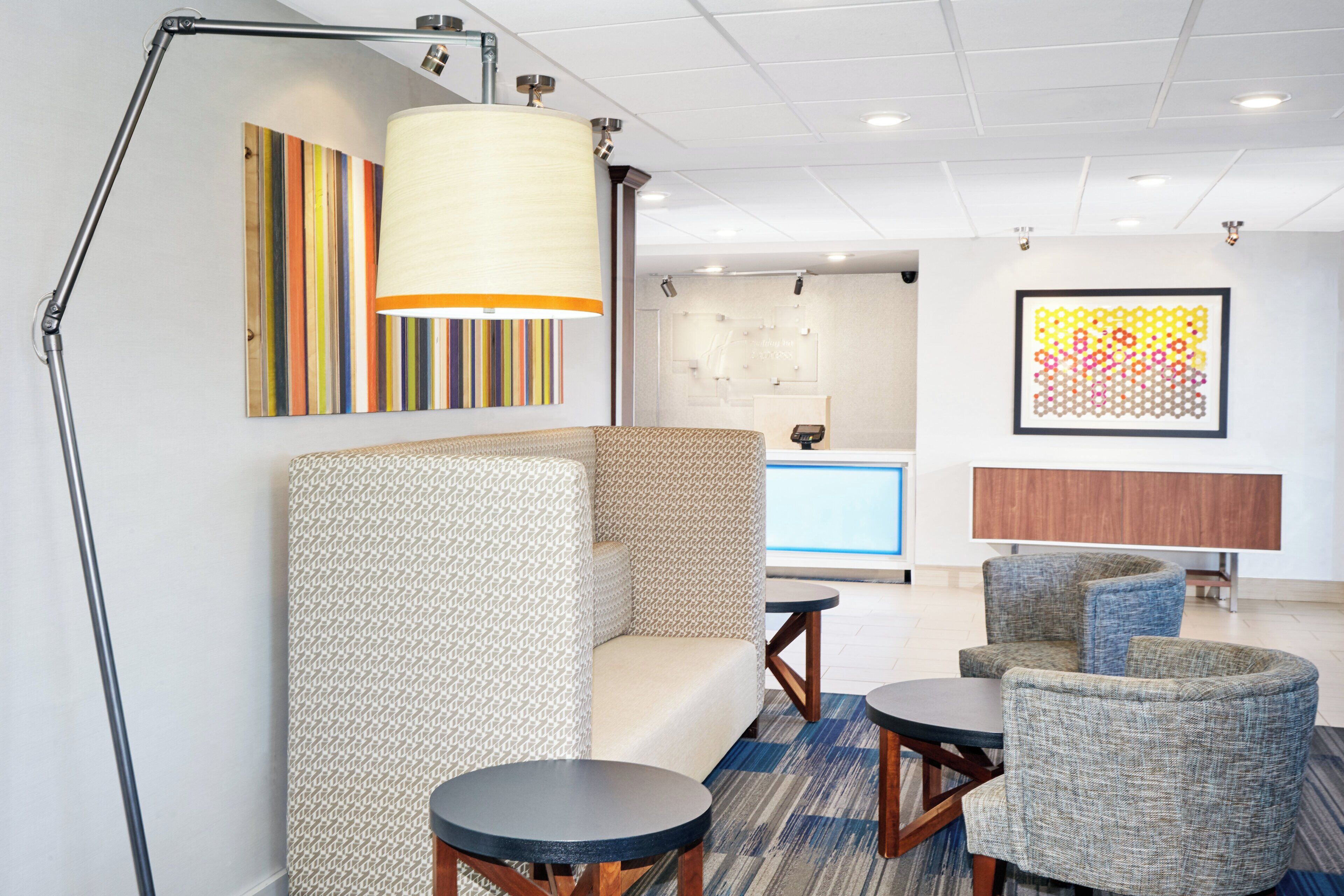A modern lobby with seating arrangements, a reception desk, and artwork on the walls.