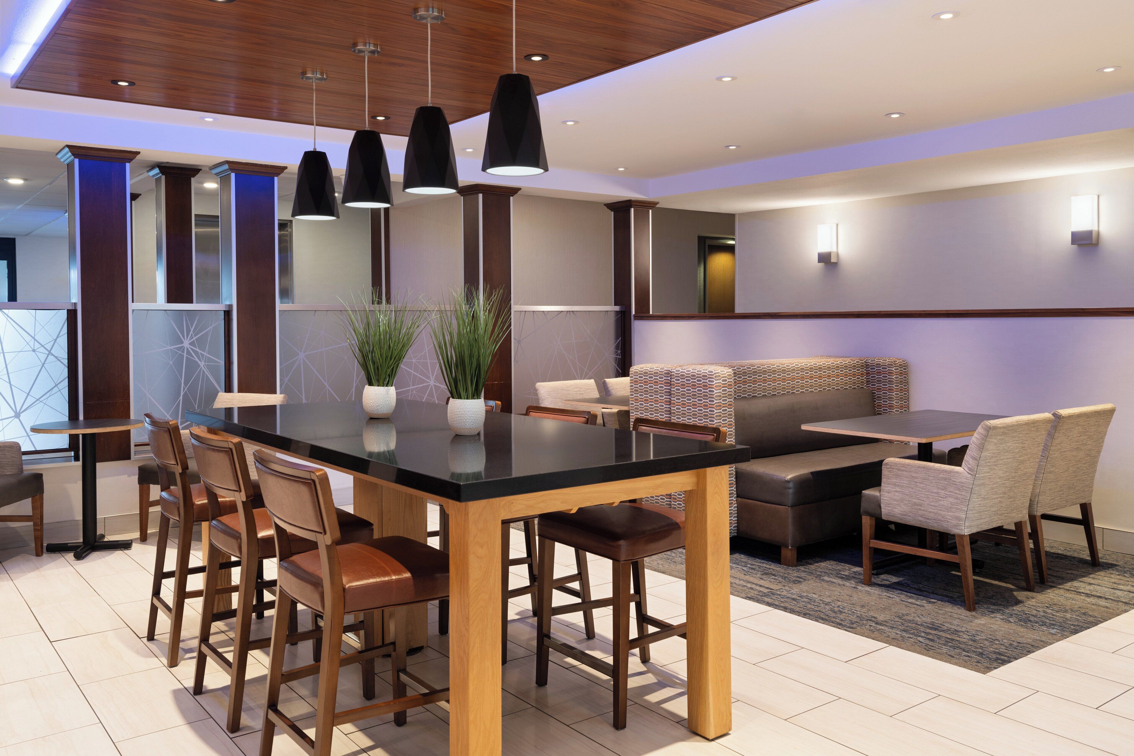 Un espace repas moderne doté d’un îlot central, de tabourets de bar et d’un canapé.
