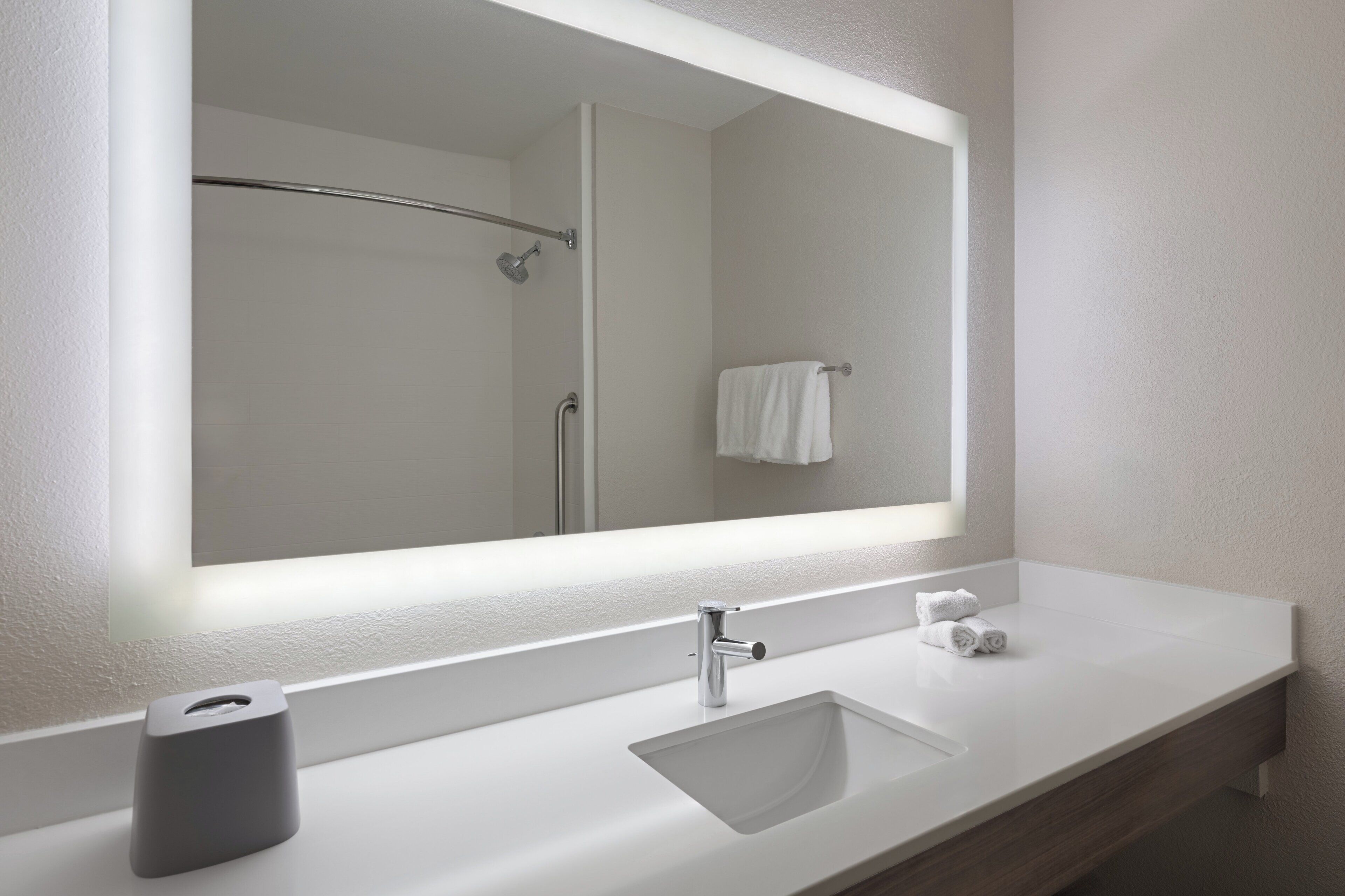 Une salle de bain moderne avec un lavabo blanc, un grand miroir et un porte-serviettes.