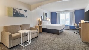 Ein Hotelzimmer mit einem Bett, einem Sofa, einem kleinen Tisch, einem Schreibtisch und einem Fernseher.