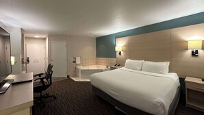 A hotel room with a large bed, a desk with a chair, a bathroom with a bathtub, and a mirror. - Best Western Watertown (Watertown)