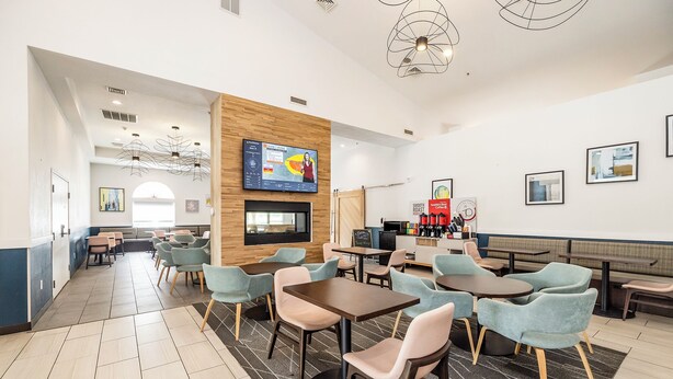 A modern hotel lobby with seating areas, a TV screen, and a coffee station. - Best Western Watertown (Watertown)