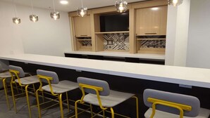A modern bar area with a white countertop and yellow chairs. - Best Western Watertown (Watertown)