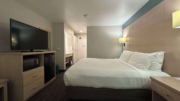 A hotel room with a bed, a television, a desk, and a wardrobe.