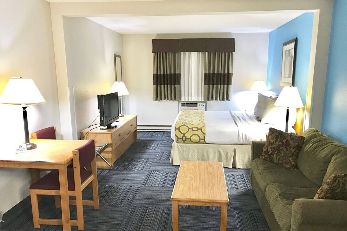 Hotelkamer met een bed, een bureau met stoel, een bank, een klein tafeltje en twee lampen.