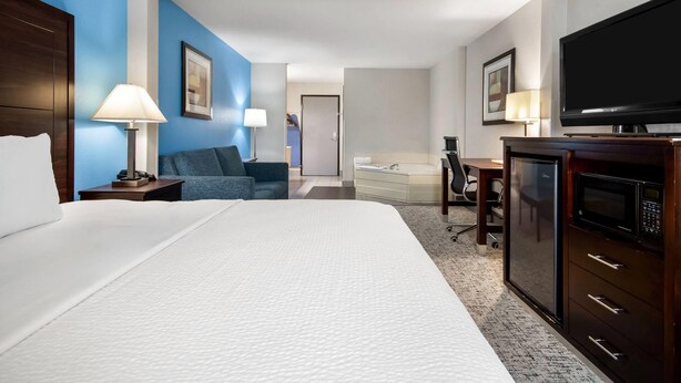 Una habitación de hotel con una cama grande, un escritorio, un televisor y un microondas.