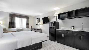 Quarto de hotel com uma cama, uma escrivaninha, um frigorífico, um micro-ondas e uma pia.