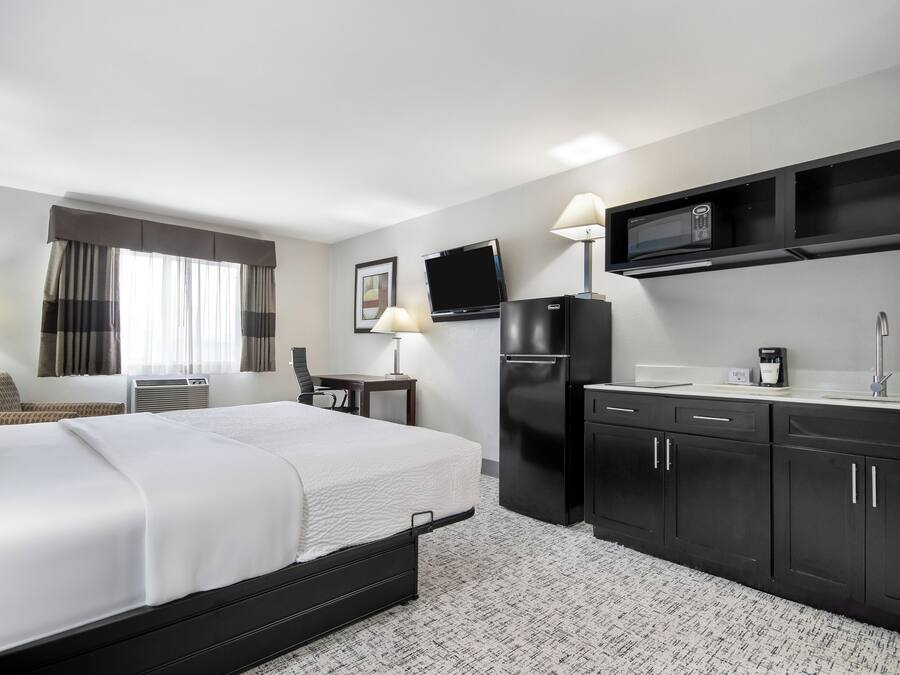 Quarto de hotel com uma cama, uma escrivaninha, um frigorífico, um micro-ondas e uma pia.
